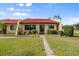 Front exterior showcasing the charming home with a well-manicured lawn, tidy shrubbery, and stone walkway at 1302 58Th W St, Bradenton, FL 34209