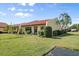 Charming home featuring a red tile roof, lush green lawn, and tropical palm trees at 1302 58Th W St, Bradenton, FL 34209