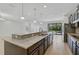 Large kitchen area with an island, stainless steel appliances, dark cabinetry, and an open view to the living area at 15608 31St E St, Parrish, FL 34219