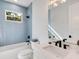 A modern bathroom with blue tile, leaf-print wallpaper, a soaking tub, and a large vanity at 2246 Webber St, Sarasota, FL 34239