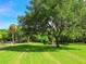 Scenic park view with lush green lawn, mature trees, a pond with fountain, and a walking path under a bright, sunny sky at 2246 Webber St, Sarasota, FL 34239