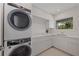 Modern laundry room features white cabinets, sink, and stacked washer and dryer at 2590 Floyd St, Sarasota, FL 34239