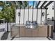 Outdoor kitchen featuring stainless steel grill, sink, and refrigerator in a covered area at 2590 Floyd St, Sarasota, FL 34239