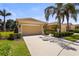 Inviting single-story home showcasing a spacious driveway, two-car garage, and lush tropical landscaping at 27243 Ipswich Dr, Englewood, FL 34223