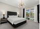 Bedroom featuring a decorative light fixture, neutral walls and direct access to backyard at 3415 Big Sky Way, Bradenton, FL 34211