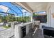 Outdoor kitchen featuring granite countertops, stainless steel grill, and comfortable seating area at 3415 Big Sky Way, Bradenton, FL 34211