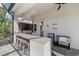 Covered outdoor kitchen with granite countertops, a built-in grill, bar seating, and convenient mini-fridge at 3415 Big Sky Way, Bradenton, FL 34211