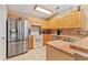 Kitchen view showcasing stainless steel refrigerator, range, and wooden cabinetry at 4211 Kingsfield Dr, Parrish, FL 34219