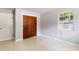 Bedroom with neutral paint, terrazzo floors, wooden closet doors, and window air conditioning at 4229 Alna Way, Sarasota, FL 34232