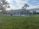 A large, grassy backyard with a screened-in patio and mature palm trees at 4411 Dolphin Ln, Palmetto, FL 34221