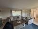 Comfortable living room with blue area rug, neutral colored furniture, and sliding glass doors to the lanai at 4411 Dolphin Ln, Palmetto, FL 34221
