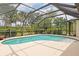 An inviting kidney-shaped pool with a screened enclosure surrounded by lush landscaping and a concrete pool deck at 4415 Charing Cross Rd, Sarasota, FL 34241