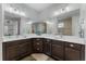 Bathroom with double sinks, stylish mirrors, and walk-in shower with decorative tile work at 4515 Roycroft Ter, Parrish, FL 34219