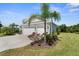 Side exterior view of the home featuring lush landscaping, mature palm trees, and a well-maintained lawn at 4515 Roycroft Ter, Parrish, FL 34219