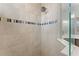 Modern shower features neutral tile and glass with decorative accent border at 4515 Roycroft Ter, Parrish, FL 34219
