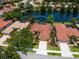 Beautiful aerial view of a home with a red tile roof, lush landscaping, and a serene lake at 521 Habitat Blvd, Osprey, FL 34229