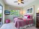 Bright bedroom features a ceiling fan, TV, sliders to the lanai, and pink and white bedding at 521 Habitat Blvd, Osprey, FL 34229