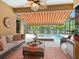 Covered patio with comfortable seating, a retractable awning, and scenic views of the pool and lake at 521 Habitat Blvd, Osprey, FL 34229