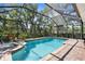 Sparkling pool in screened enclosure, surrounded by brick pavers and a view of nature at 5945 Nyberg Rd, North Port, FL 34286