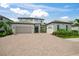 Stunning two-story home with a three-car garage and a brick-paved driveway, enhanced by lush landscaping at 6152 Lungo Lago Dr, Sarasota, FL 34241