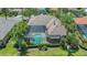 Aerial view of screened-in pool and spa with clay tile roof, garden, and palm trees at 6633 The Masters Ave, Lakewood Ranch, FL 34202