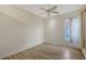 This bedroom features neutral paint, wood-look floors, ceiling fan, and a window with natural light at 6633 The Masters Ave, Lakewood Ranch, FL 34202