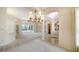 Open-concept living space with neutral carpet, an elegant chandelier, and sliding doors to the pool area at 6633 The Masters Ave, Lakewood Ranch, FL 34202