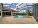 Screened-in pool with a spa, brick pavers, and an outdoor kitchen with bar seating at 6633 The Masters Ave, Lakewood Ranch, FL 34202