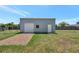 Backyard shot of a steel shed with a roll up door and gravel access on a verdant lawn at 7055 Kenwood Dr, North Port, FL 34287