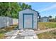 White shed with blue trim and a hanging lantern; storage shed is visible in the background at 7055 Kenwood Dr, North Port, FL 34287