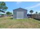 New gray storage shed with a roll-up door and grassy surrounding at 7055 Kenwood Dr, North Port, FL 34287