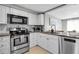 Kitchen boasts granite countertops, stainless steel appliances, white cabinets, and tiled backsplash at 709 84Th Nw St, Bradenton, FL 34209