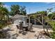 Outdoor patio with fire pit table, gas grill, and pergola for shaded seating, surrounded by lush landscaping at 709 84Th Nw St, Bradenton, FL 34209