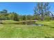 Sprawling green backyard leading to a pond surrounded by trees and lush vegetation at 7374 Royal Birkdale Dr # 15D, Sarasota, FL 34238