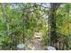 Tranquil backyard garden featuring a metal arbor, lush greenery, and a stone pathway at 9915 Old Hyde Park Pl, Bradenton, FL 34202