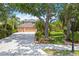 A view of the exterior with a well-manicured lawn, mature trees, and a spacious driveway at 9915 Old Hyde Park Pl, Bradenton, FL 34202