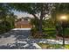 A view of the exterior with a well-manicured lawn, mature trees, and a spacious driveway at twilight at 9915 Old Hyde Park Pl, Bradenton, FL 34202
