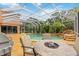 Beautiful screened-in pool area with lush landscaping and a cozy seating area with fire pit for outdoor entertaining at 9915 Old Hyde Park Pl, Bradenton, FL 34202