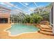 A screened pool with a rock waterfall feature and lush tropical plants at 9915 Old Hyde Park Pl, Bradenton, FL 34202