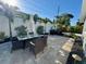 Outdoor dining set on a stone patio, with lush landscaping and privacy fencing creates an inviting space for outdoor enjoyment at 1112 65Th Nw St, Bradenton, FL 34209