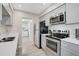 Galley kitchen with stainless steel appliances, grey cabinets, quartz countertops, and an open view to the laundry room at 1112 65Th Nw St, Bradenton, FL 34209