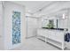 Bright bathroom featuring double sinks and a decorative stained-glass window at 1155 Lake House Cir # C119, Sarasota, FL 34242