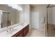 Well-lit bathroom with double sinks, vanity with cabinets, a glass-enclosed shower, and tile flooring at 116 Navigation Cir # 106, Osprey, FL 34229