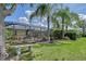 This backyard features a screened lanai, a bench, manicured lawn, and mature palm trees at 12133 Forest Park Cir, Bradenton, FL 34211