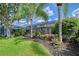 Sprawling backyard with manicured lawn, tropical landscaping, and screened lanai area at 12133 Forest Park Cir, Bradenton, FL 34211