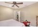 Bedroom featuring a white bed, small bench, ceiling fan, and a glimpse into a laundry room through an open door at 12133 Forest Park Cir, Bradenton, FL 34211