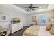 Bright main bedroom features a ceiling fan, a dresser with a TV, and a large sunny window with shutters at 12133 Forest Park Cir, Bradenton, FL 34211