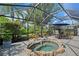 Enclosed pool area with a spa, blue umbrella, table and chairs, and tropical landscaping at 12133 Forest Park Cir, Bradenton, FL 34211
