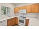 Bright kitchen featuring white appliances and wooden cabinets with wood laminate flooring at 12358 Destiny Dr, Venice, FL 34292