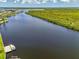 Scenic aerial view of a wide canal with a boat dock, lush greenery, and cloudy skies at 127 Colonial Sw St, Port Charlotte, FL 33952